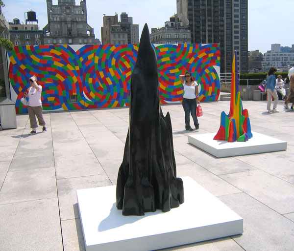 a sculpture stands in the center of a public area in the city