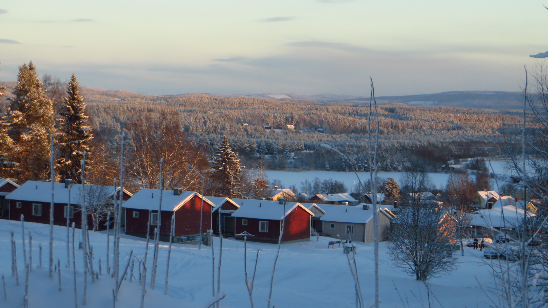 a row of wooden buildings in snow covered countryside