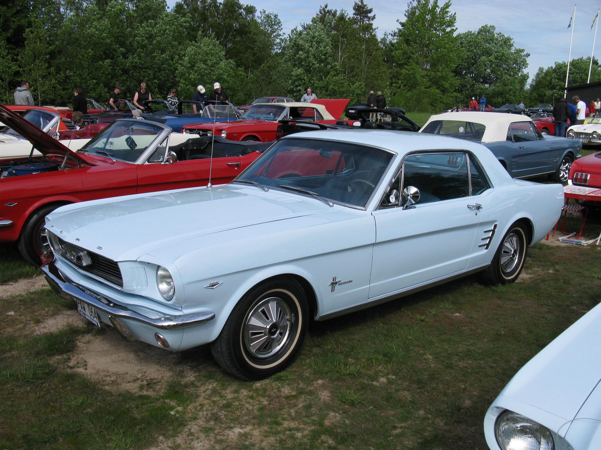 an old mustang mustang sits in front of other vintage mustangs