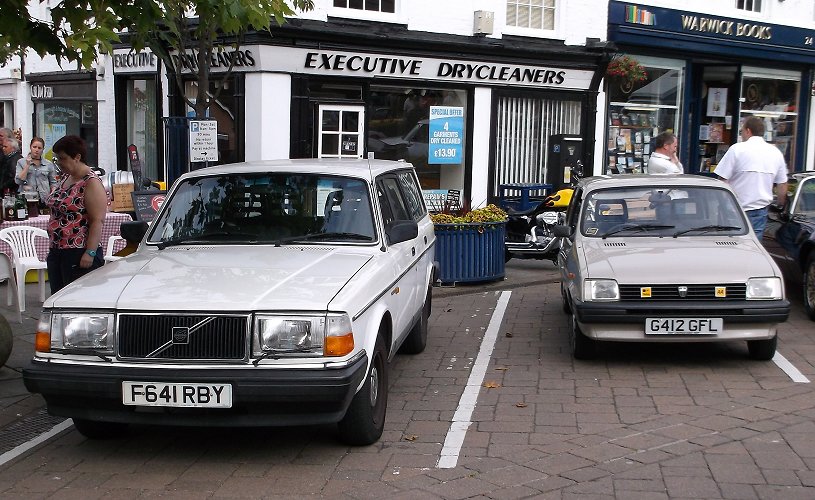 two cars parked outside of a small retail place