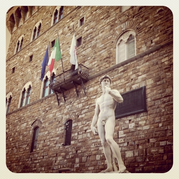 a statue of a man standing in front of an old brick building