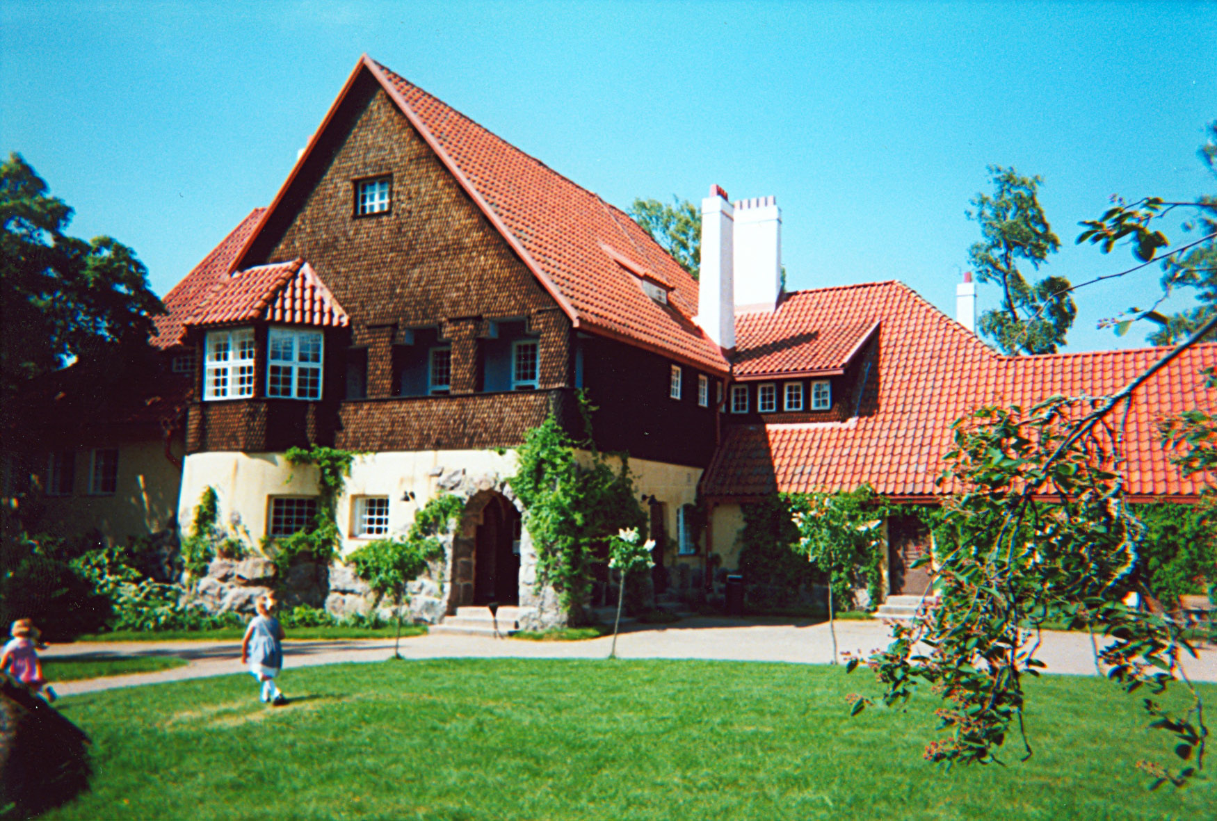 people walking on the lawn next to a large house