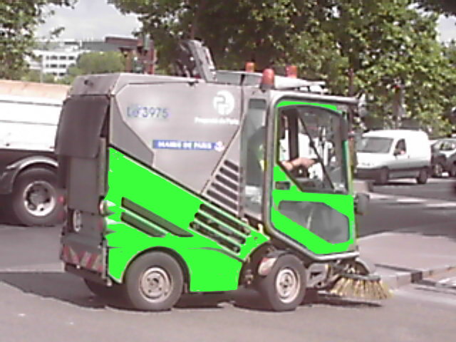 a green street sweeper being used by people