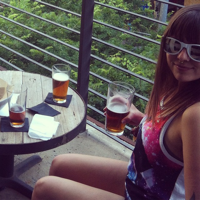 two girls drink some beer on a balcony