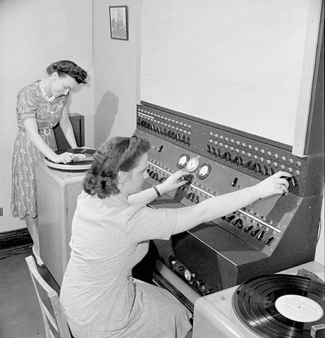 an old picture shows two women at a control panel
