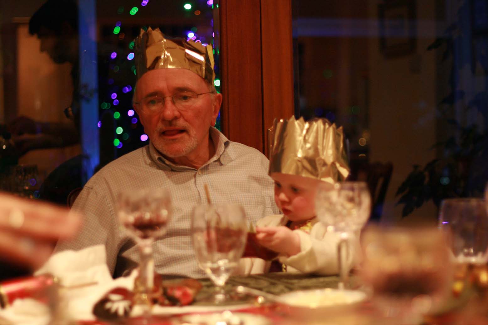 a older man is dressed up as a crown while sitting at a table with many other people