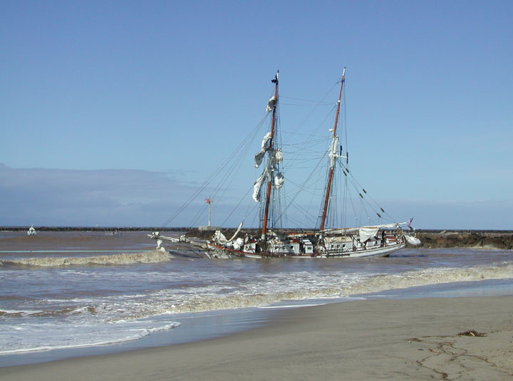 a sailboat rests on the beach beside an ocean