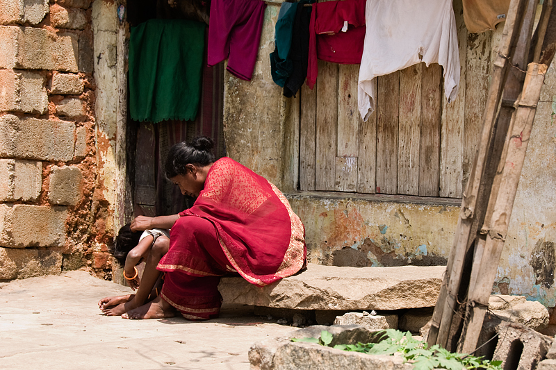 a woman sitting in front of a building and clothing hanging from a line