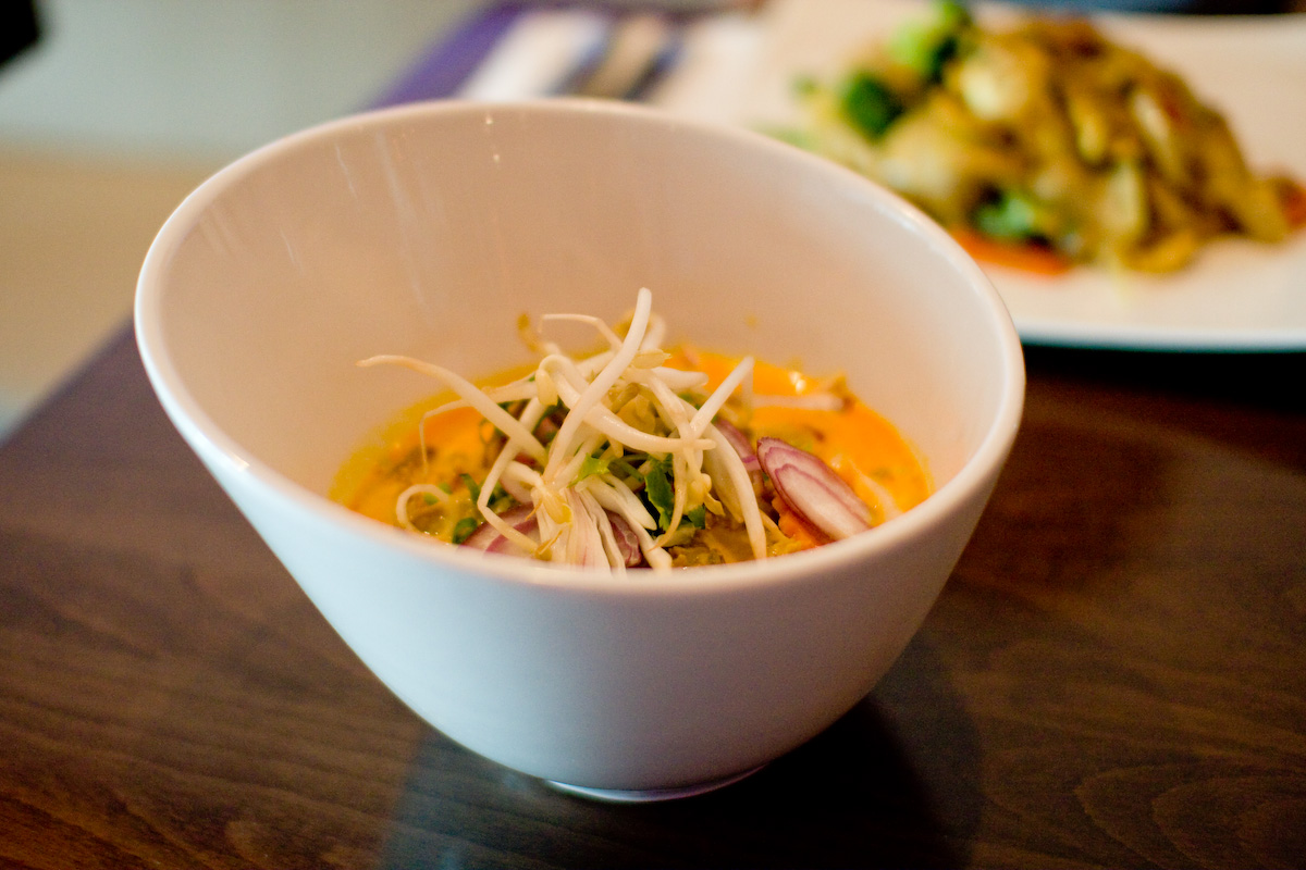 bowl of food on wooden table near plate of vegetables