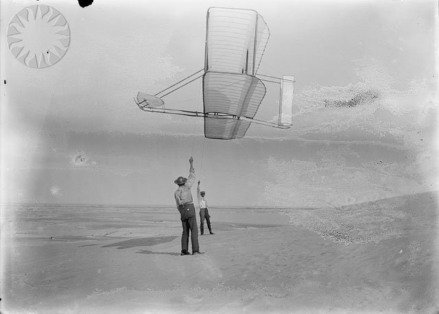 an old black and white po shows two men flying a kite