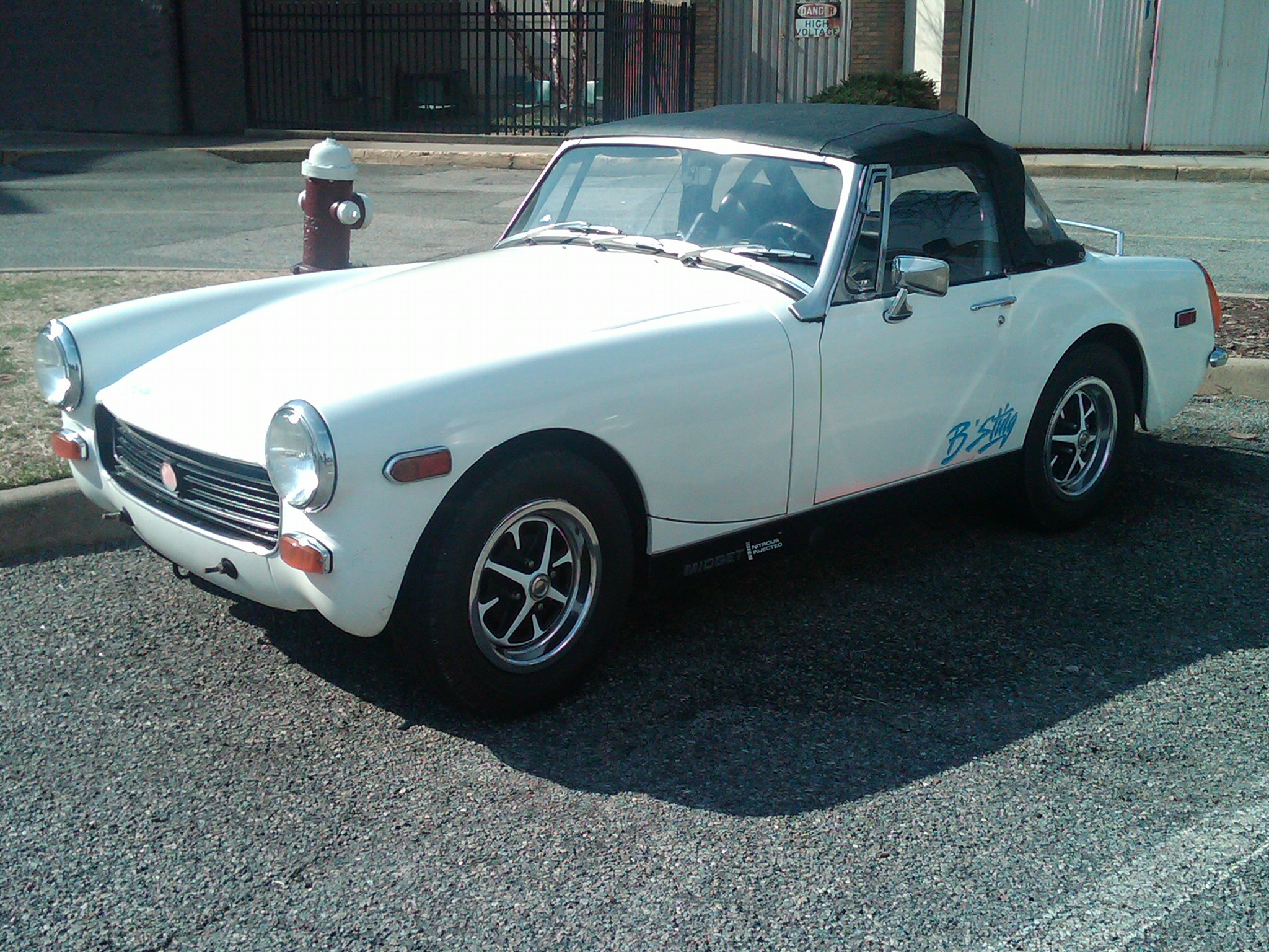 the classic white sports car is parked in front of a fire hydrant