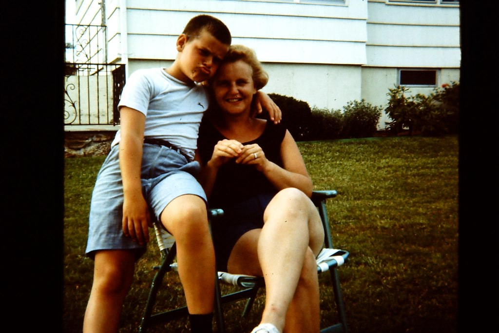 young man hugging his mother in front of their house