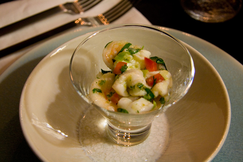 some shrimp with tomatoes, cucumbers and spinach in a glass on a plate