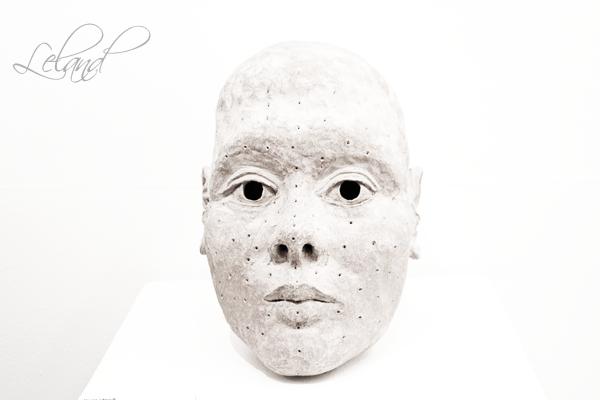 a white porcelain mask with freckles of black spots on it