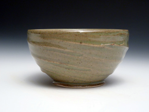 a light brown stoneware bowl with dark green rim