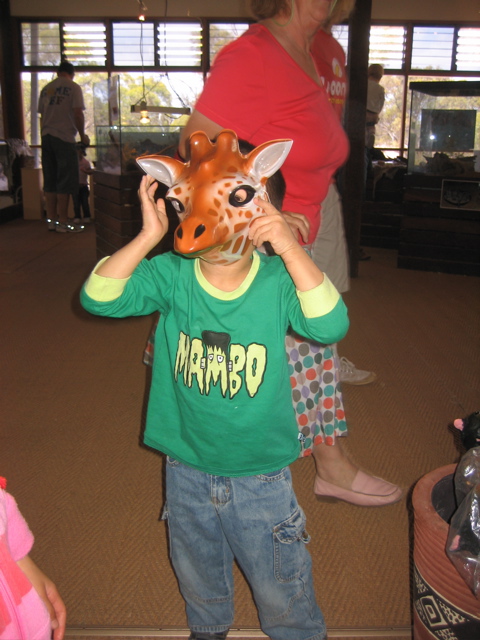 a child holds his head up in front of a giraffe mask