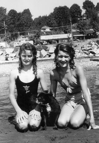 the girl are sitting on the beach with the dog