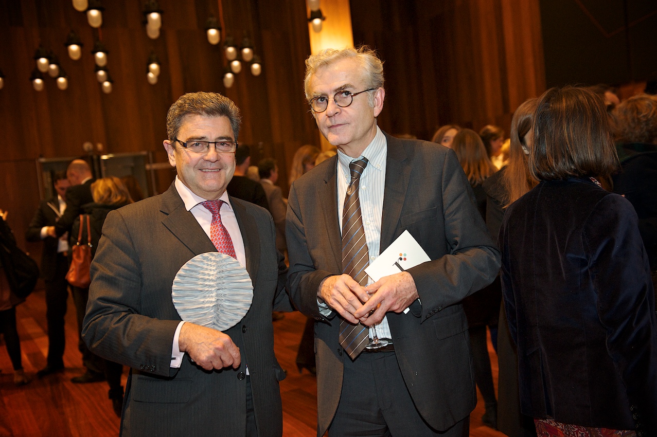 two men in suits holding small ribbons and badges