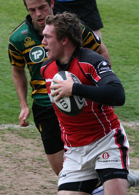 a rugby player running with a football in his hand