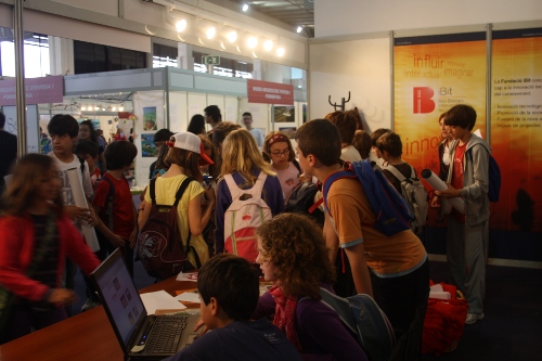 a group of people stand in a crowded room looking at computer screens
