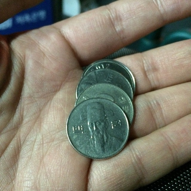 a person holding onto three indian rupee coins