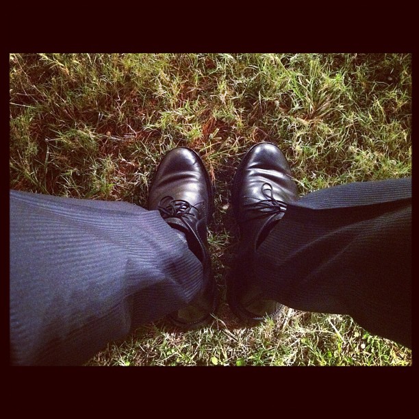 a man wearing black shoes standing in the grass