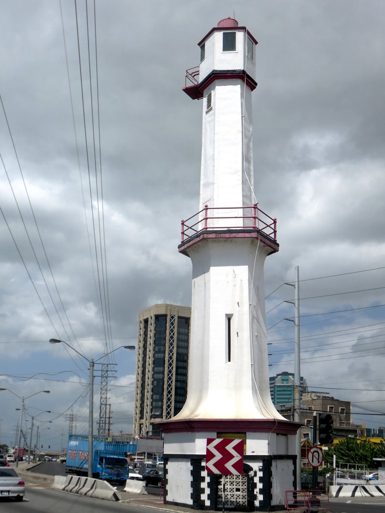 a tall white lighthouse sitting on the side of a road