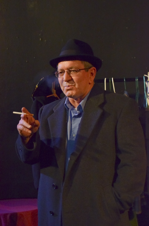 a man with glasses and suit smoking a cigarette