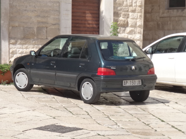 the small blue hatchback car is parked in a stone street