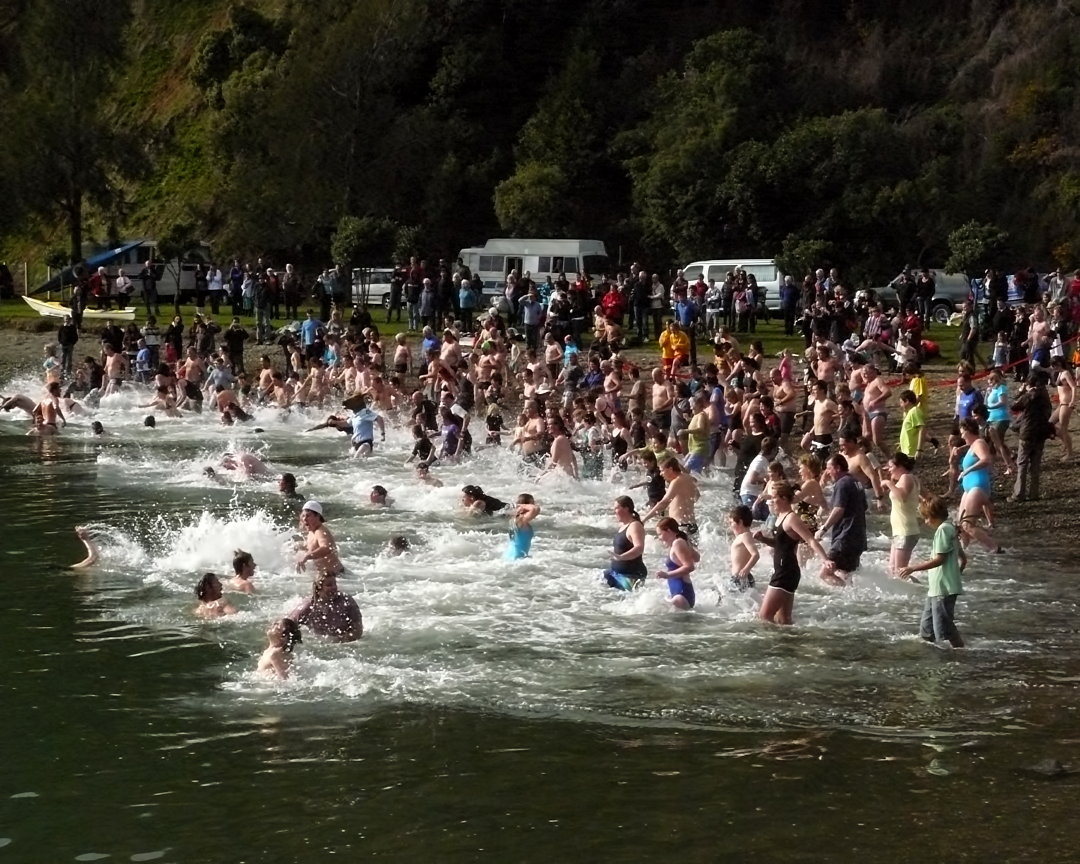 large group of people in body of water with one of them swimming in a lake