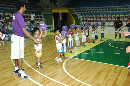 a group of children with two men and two women holding up basketballs