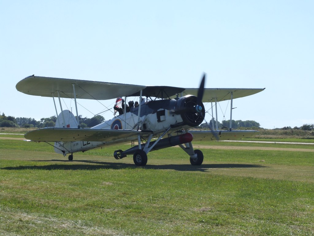 a small propellor airplane parked on a grassy field