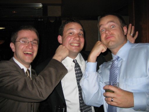 three men are smiling and hugging at a social event