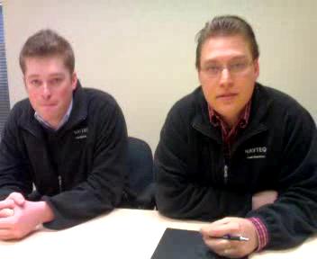 two young men sitting at a table looking off into the distance