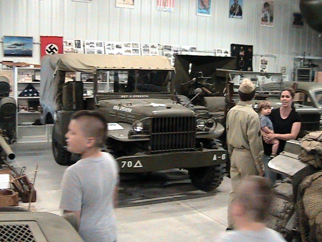 a group of people are walking around an army vehicle