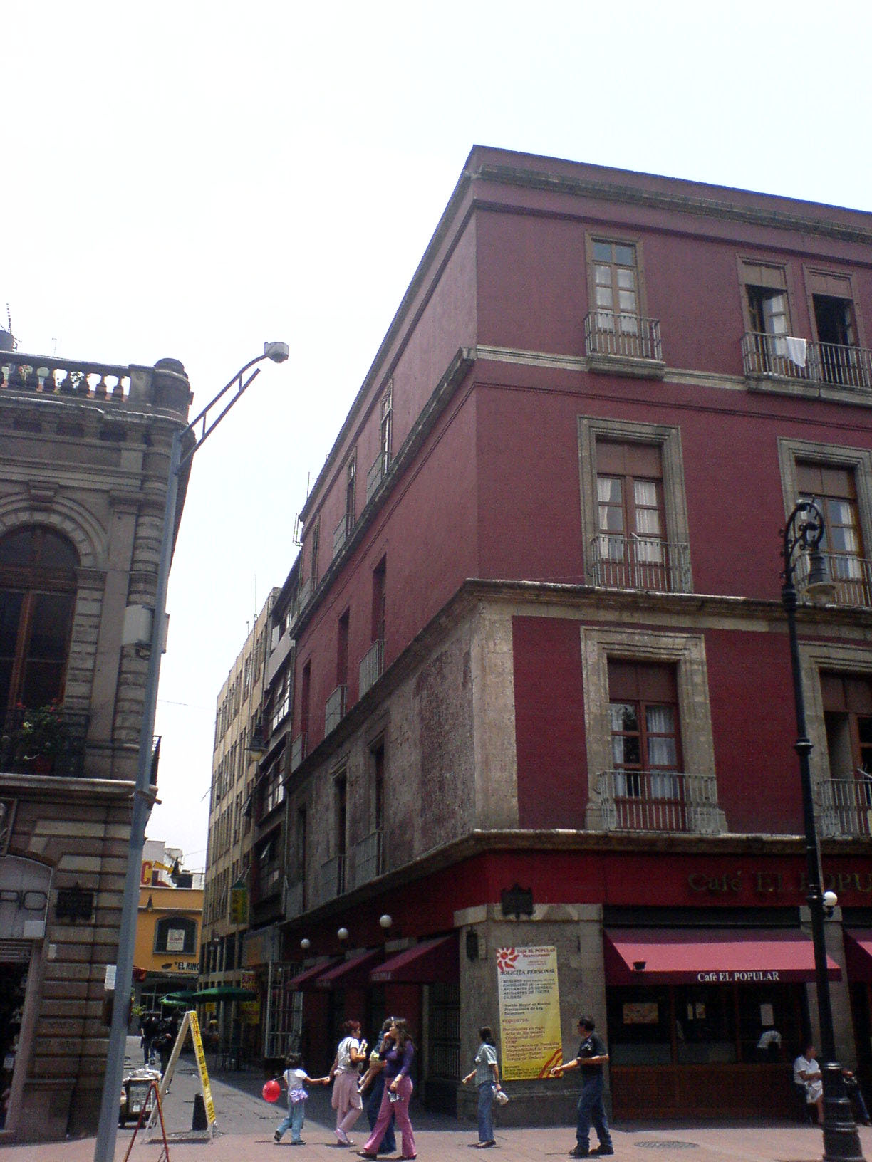 people walk along the street next to some old buildings