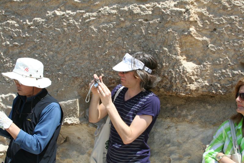 three people are standing against a large rock