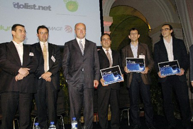 six men with their laptops standing on stage