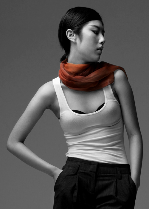a woman wearing a top and scarf with her hands on her hips