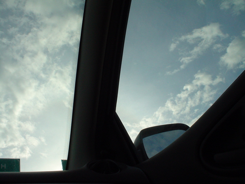 looking out the car window at a sky with clouds