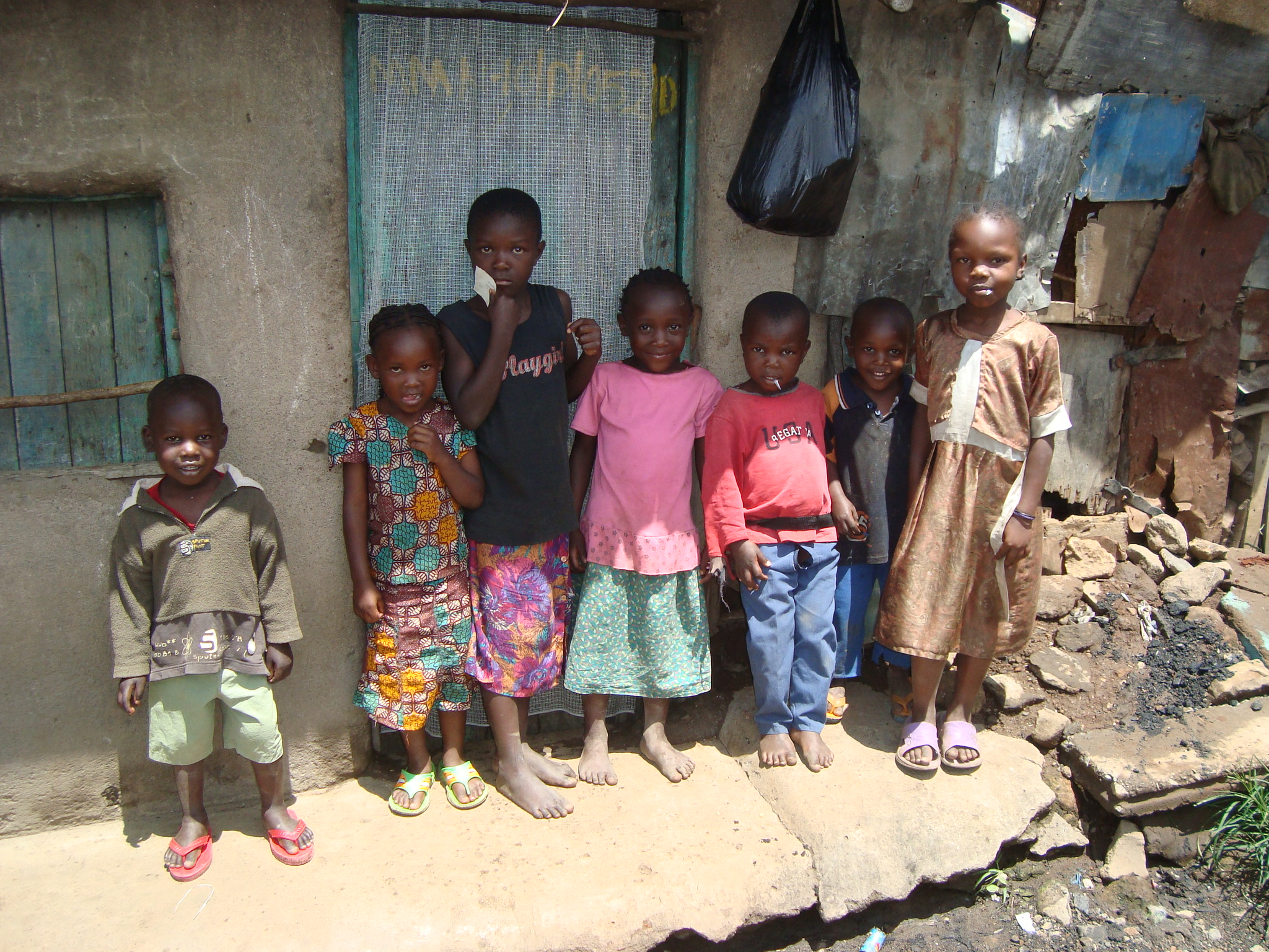 group of children standing in front of a small mud hut