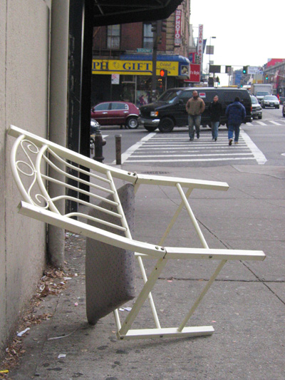 an ironing bench is set on the sidewalk near a wall