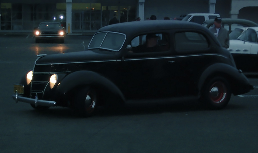 a very old model car on the road at night