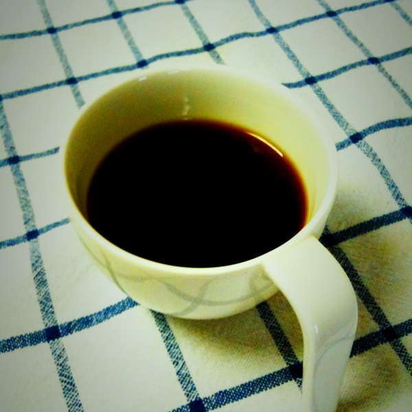 a cup of coffee sits on a checkered tablecloth