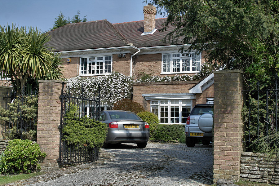 a car parked on a gravel driveway in front of a house