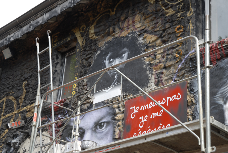 an urban scaffolding with pictures and graffiti is pictured