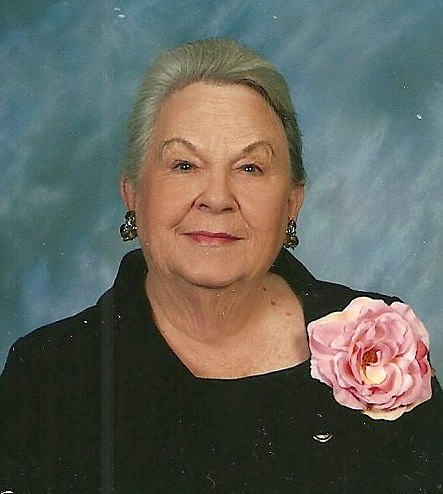 an older woman wearing a black shirt and pink flower
