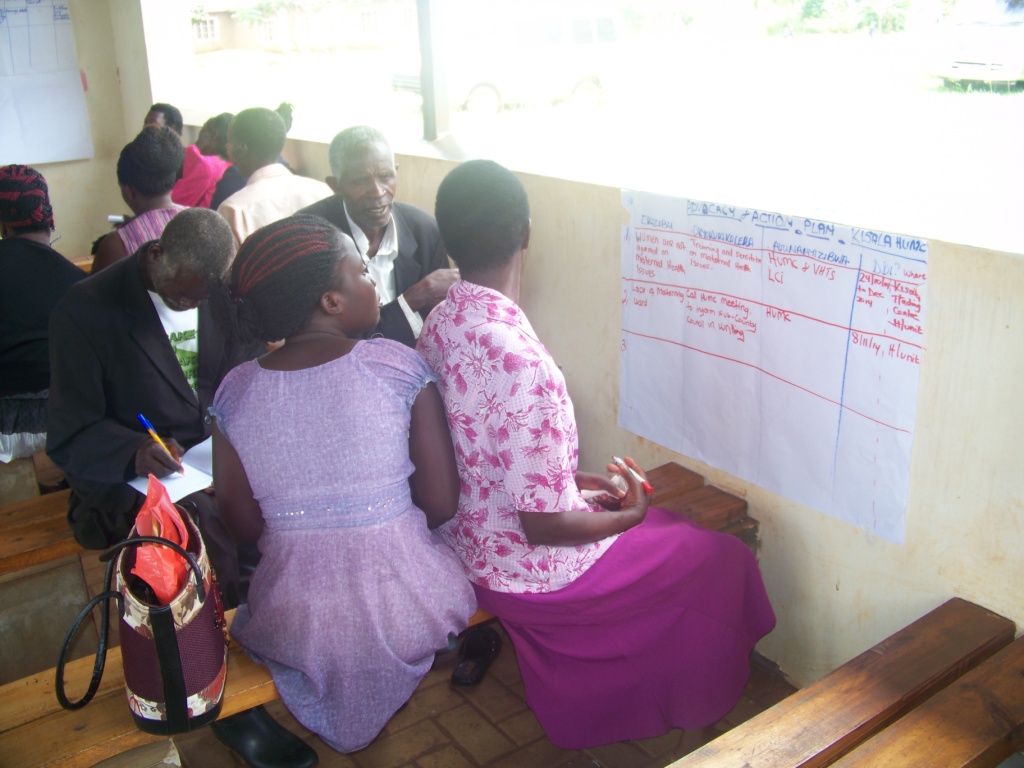 a group of people sitting at a table next to a whiteboard