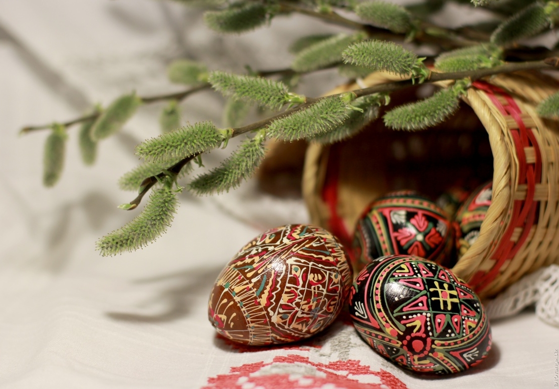 three decorated eggs with a basket in the middle of them