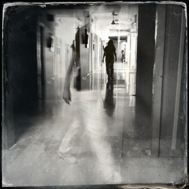 a woman walking down a hallway holding onto a bag